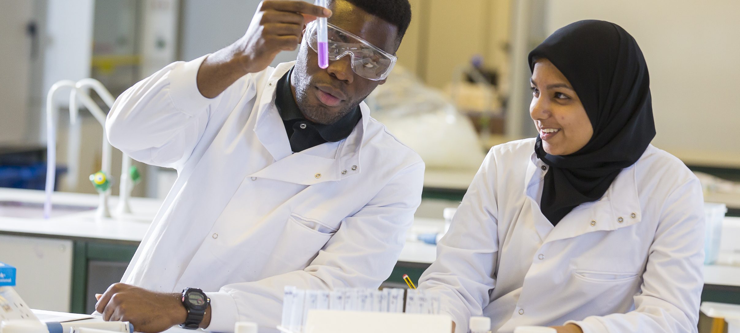 Two people in lab coats doing a science experiment